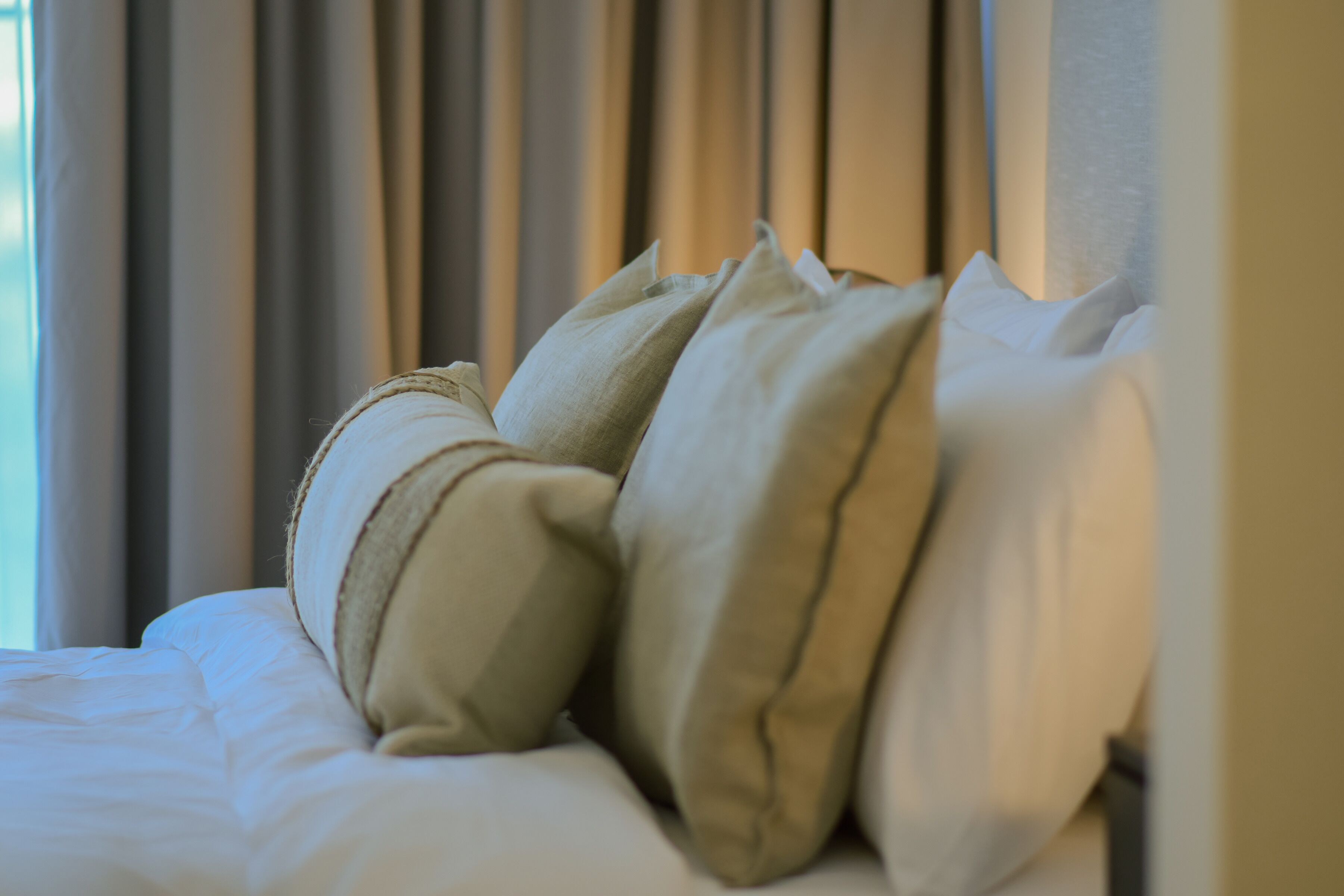 Un lit avec une literie et des oreillers aux couleurs beige et blanche.