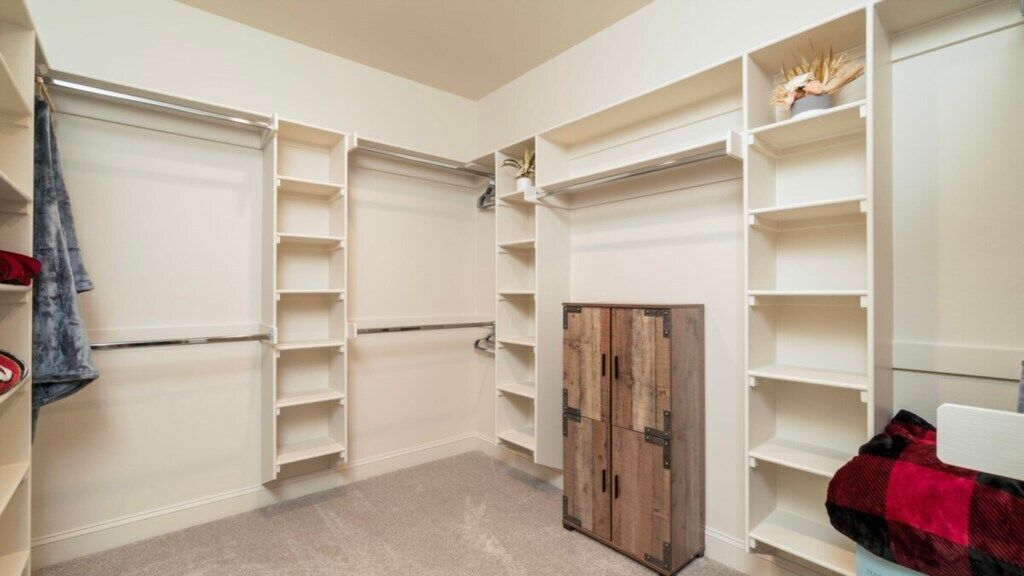 A walk-in closet with multiple shelves and a wooden cabinet.
