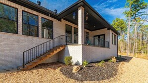 Une maison moderne avec une façade en briques, un escalier en bois et un porche abrité.