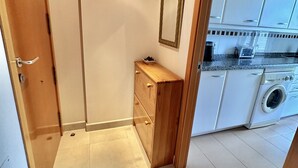 Une cuisine compacte équipée d’un lave-linge, d’un meuble en bois et d’un miroir mural.