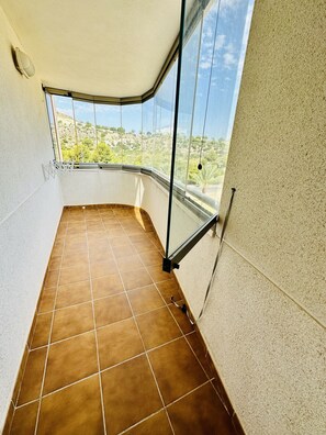 A balcony with a tiled floor, glass railings, and a view of a hilly landscape. - A1039 - Quality flat with garage and swimming pool (Villajoyosa)