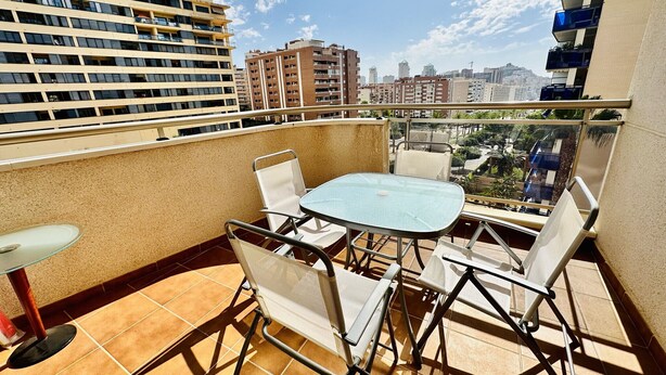 A balcony with a table and chairs, a view of surrounding buildings, and a clear sky. - A1039 - Quality flat with garage and swimming pool (Villajoyosa)