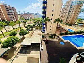 A high-rise building with a rooftop pool and surrounding greenery.