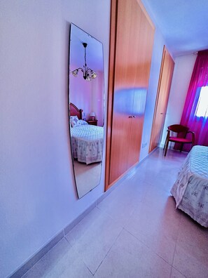 A bedroom with a bed, a nightstand, a chair, a large mirror, and a wardrobe. - A1039 - Quality flat with garage and swimming pool (Villajoyosa)