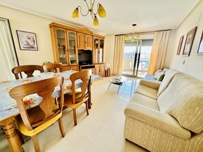 A living room with a dining area, wooden cabinets, a television, and a sofa. - A1039 - Quality flat with garage and swimming pool (Villajoyosa)