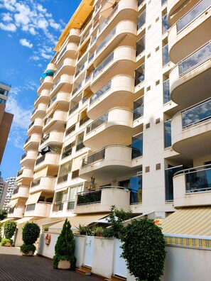 Un immeuble résidentiel à plusieurs étages, doté de balcons, d’un toit plat et surplombant un ciel dégagé.