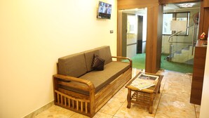 A living room with a sofa, a coffee table, and a television mounted on the wall. - Hotel Air Stay Inn (Mumbai)