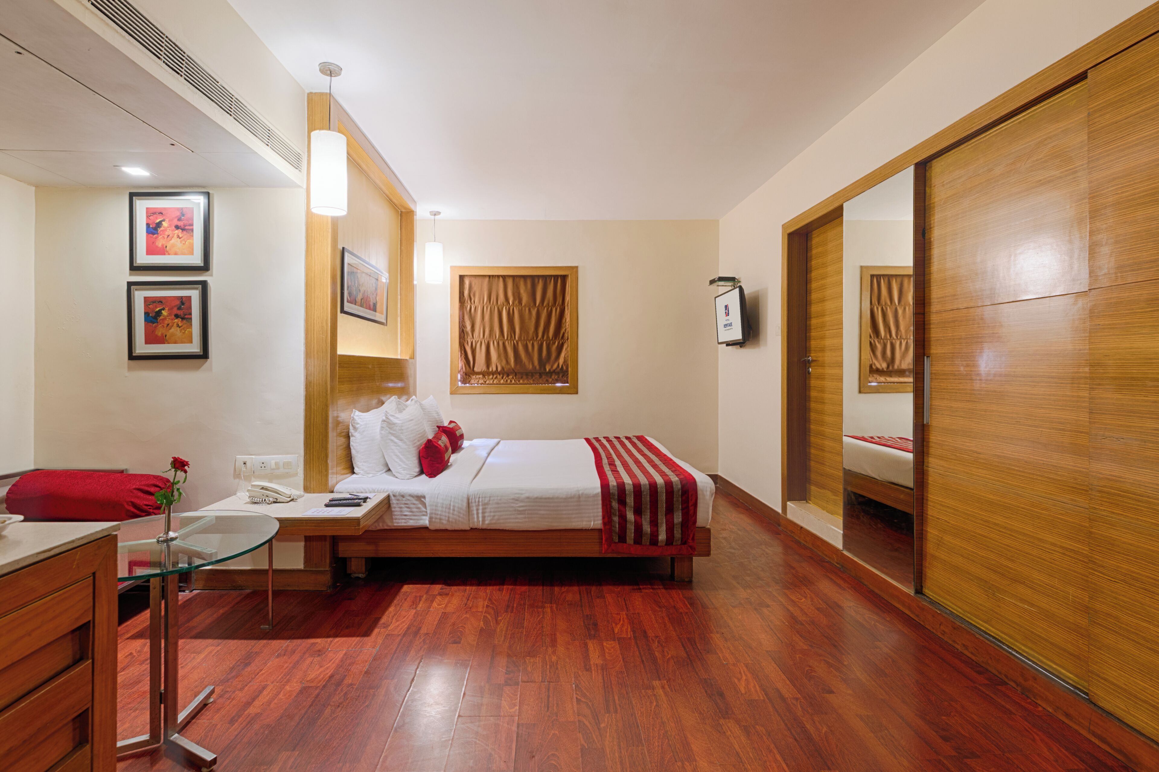 Una habitación de hotel con una cama, mesita de noche y un espejo.