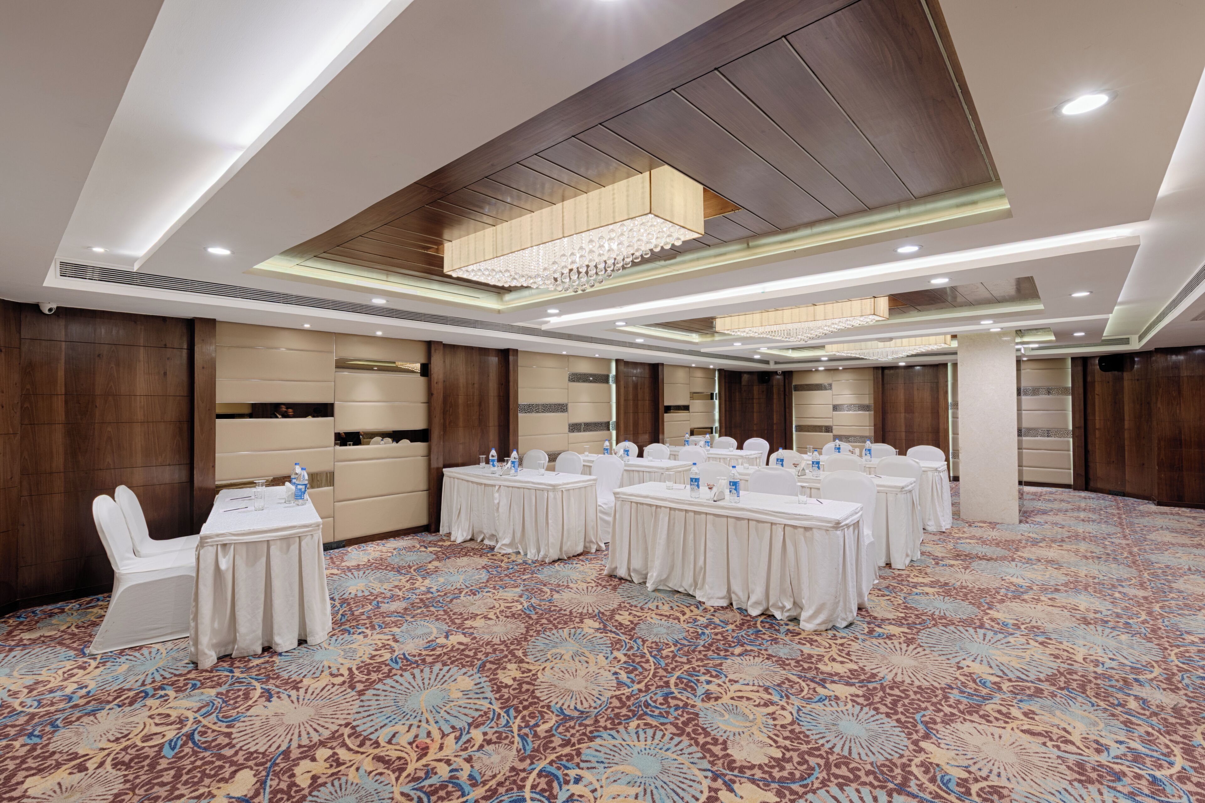 Une salle de conférence avec des tables rondes, des chaises blanches et un tapis à motifs.