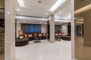 A modern living room with a sectional sofa, a round coffee table, and a large window with curtains.