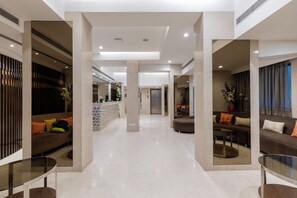 A modern hotel lobby with a central reception desk, seating areas, and a glass coffee table. - Hotel Heritage formerly known as Comfort Inn Heritage (Mumbai)