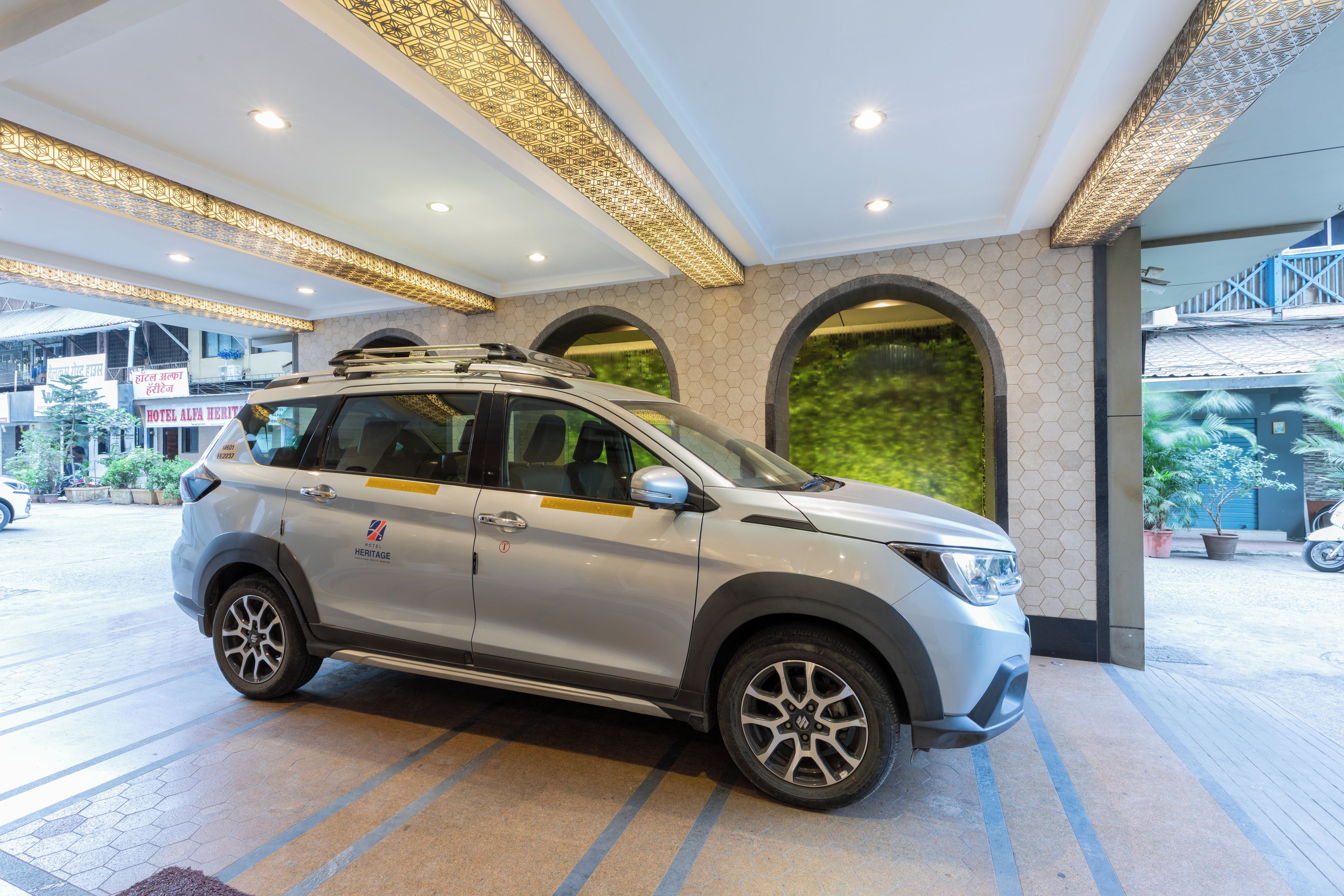 A silver SUV parked in a hotel lobby with a modern design, including hexagonal patterned walls and a large arched window.