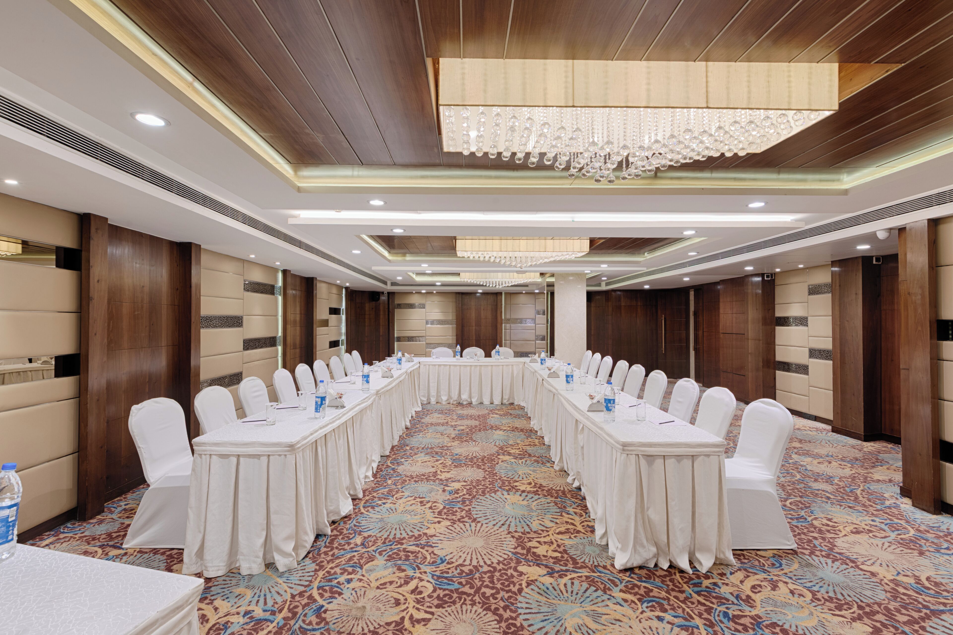 A conference room with a long table, white chairs, and a chandelier.