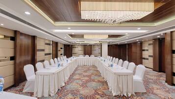 A conference room with a long table, white chairs, and a chandelier.