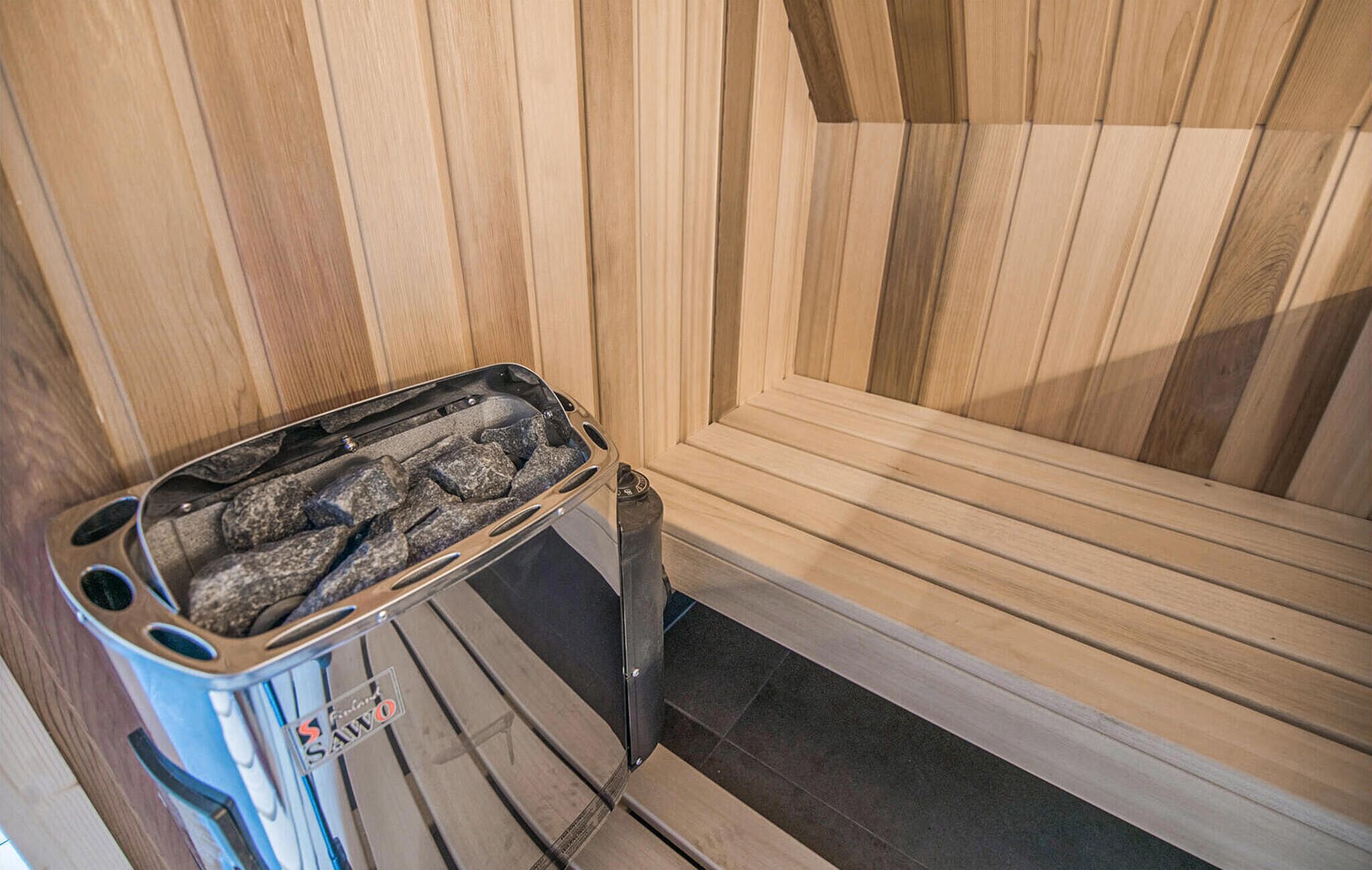Un sauna avec un intérieur en bois et un banc en métal doté d’un élément chauffant.