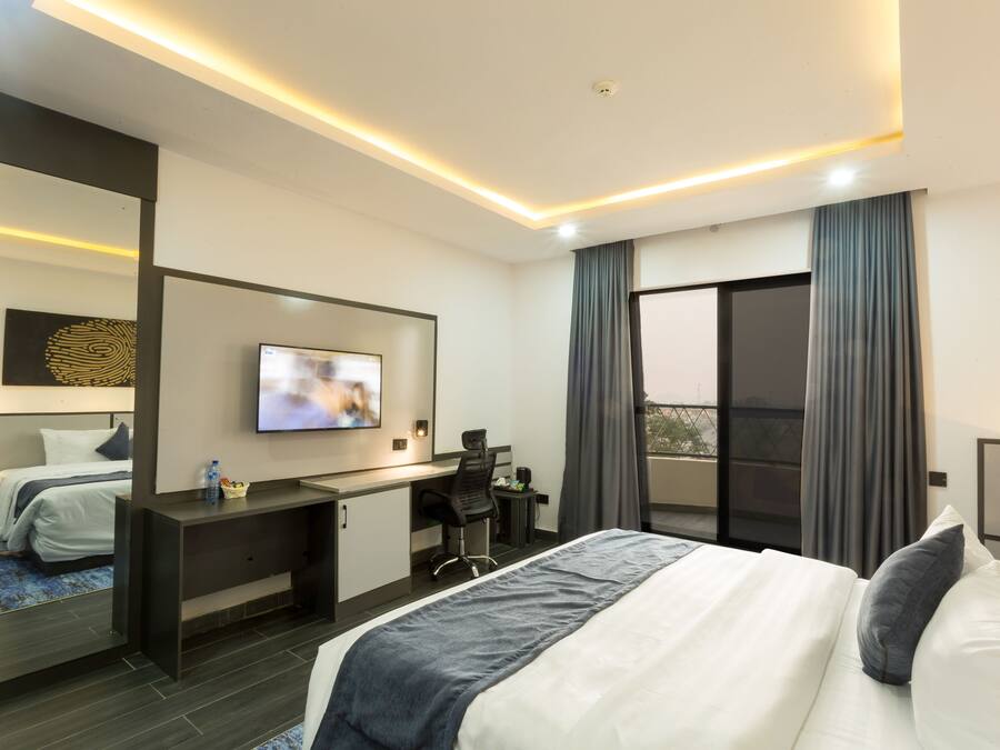 Habitació d'hotel moderna amb llit, escriptori i televisió.