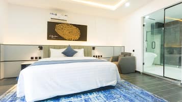 Habitación de hotel moderna con una cama grande, cabina de ducha de vidrio y aire acondicionado de pared.