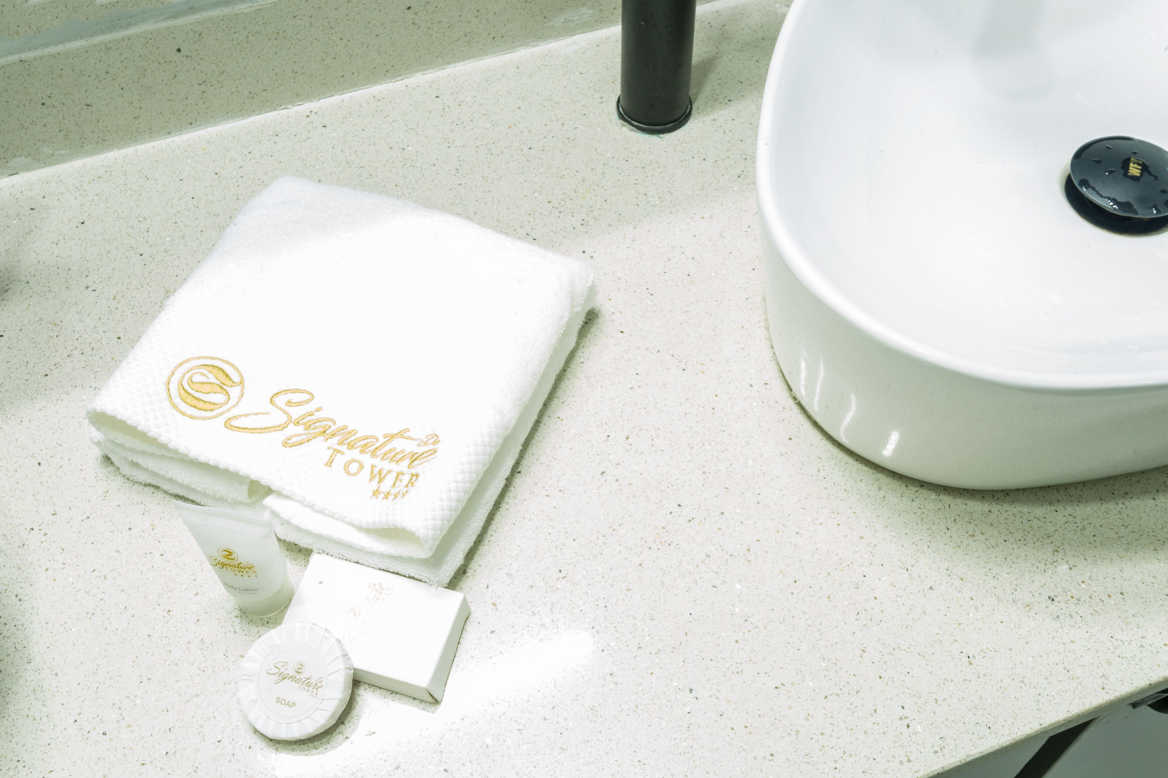 A bathroom counter with a white towel, a soap dispenser, and a sink.