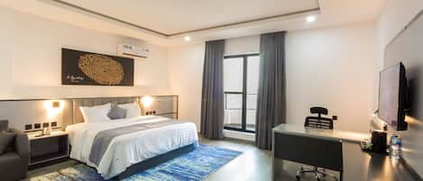 A modern hotel room with a bed, desk, and chair, a large window with curtains, and a mounted TV.