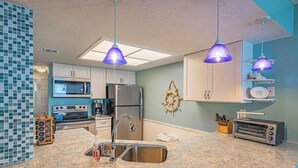 Eine Küche mit Granit Arbeitsplatten, Edelstahlgeräten und Pendelleuchten.