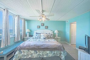 A bedroom with a bed, nightstands, a ceiling fan, and a view of the ocean. - Oceanfront condo at Southpoint unit 606 (Ponce Inlet)