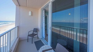 Ein Balkon mit Blick auf den Strand, ein Stuhl und ein Tisch.