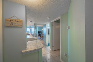 Un couloir donnant sur une cuisine, un coin repas et une salle de bain.