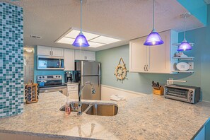 A kitchen with granite countertops, stainless steel appliances, and pendant lighting. - Oceanfront condo at Southpoint unit 606 (Ponce Inlet)