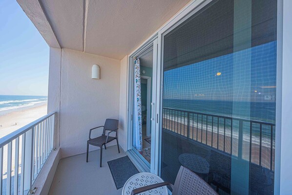 A balcony with a view of the beach, a chair, and a table. - Oceanfront condo at Southpoint unit 606 (Ponce Inlet)
