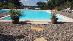 A rectangular pool with a clear blue water surface, surrounded by a pebble ground, and two potted plants on either side. - Maison de Vacances au Calme , à 5 Minutes de la Capitale de la Préhistoire ! (Tursac)