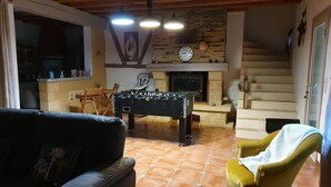 A cozy living room with a foosball table, a yellow armchair, a fireplace, and a staircase. - Maison de Vacances au Calme , à 5 Minutes de la Capitale de la Préhistoire ! (Tursac)