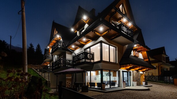 A modern multi-story building with a prominent balcony and a well-lit entrance. - Willa Folk & Prestige (Zakopane)