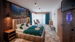 A bedroom with a large bed, a wooden wardrobe, a TV, and a painting of mountains. - Willa Folk & Prestige (Zakopane)