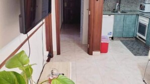 A narrow hallway leading to a kitchen with teal cabinets and a tiled floor. - Apartamento Prémium en la Familia Vigo (Vigo)