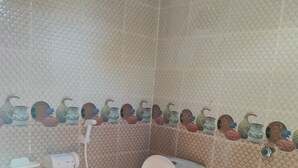 Un baño con inodoro, secamanos y dispensador de jabón en la pared.