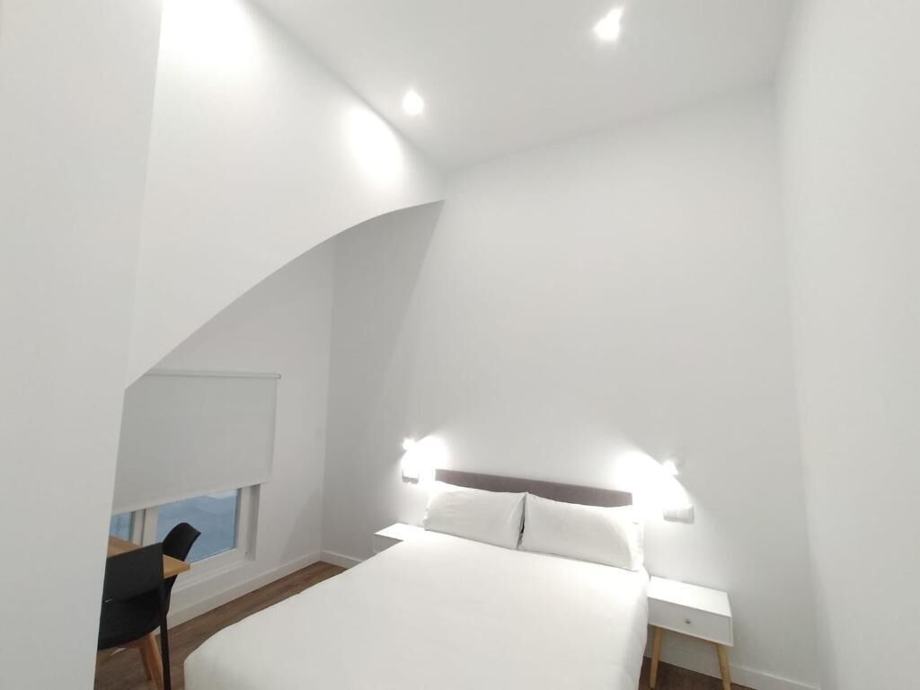 Un dormitorio con cama, mesita de noche y una silla.