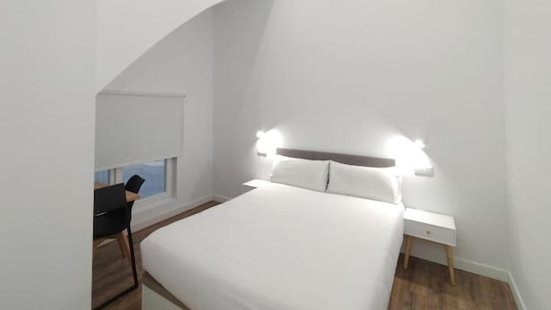 A modern bedroom with a large bed, bedside tables, and a desk with a chair. - Apartamentos Vacceas by gaiarooms (Salamanca)
