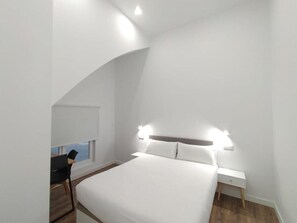 Ein modernes Schlafzimmer mit einem großen Bett, Nachttischen und einem Schreibtisch mit Stuhl.