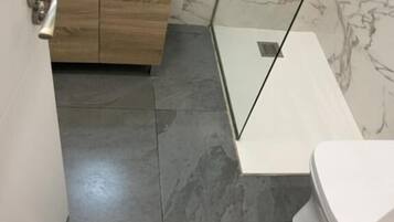 A modern bathroom with a white sink, wooden vanity, and a glass shower enclosure.