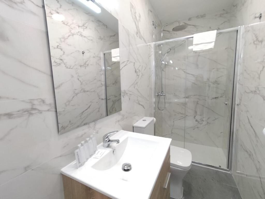 Une salle de bain moderne avec un lavabo en marbre, des toilettes et une douche à parois de verre.
