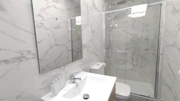 Une salle de bain moderne avec un lavabo en marbre, des toilettes et une douche à parois de verre.