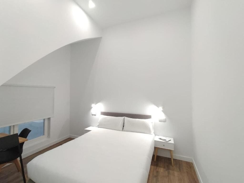 Une chambre à coucher moderne avec un lit, une table de chevet et une chaise.