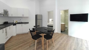 A modern kitchen with white cabinets, a black countertop, and a dining area with a black table and chairs. - Apartamentos Vacceas by gaiarooms (Salamanca)