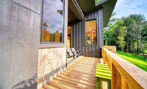 Un bâtiment moderne avec une façade en pierre, une terrasse en bois et une vue sur un paysage verdoyant.