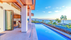 Um edifício moderno com piscina, teto de madeira e vista para o oceano.