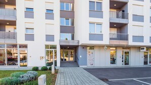 Ein modernes Mehrstöckige Gebäude mit Eingangsbereich auf Augenhöhe, einem sichtbaren Restaurant und einem Parkplatz.
