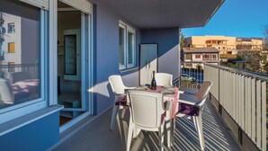 Ein Balkon mit Tisch und Stühlen, einer Flasche und Blick auf umliegende Gebäude.
