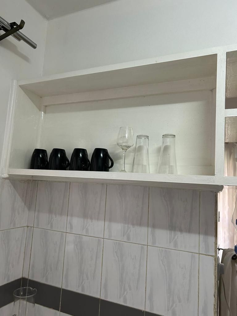 Een witte plank met zwart en helder glaswerk tegen een betegelde muur.