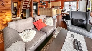 A cozy log cabin interior with a sofa, armchair, and a dining area with a table and chairs. - 4 bedroom awesome home in Rysstad (Rysstad)