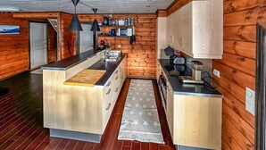 A compact kitchen with wooden walls, a central island, and modern appliances. - 4 bedroom awesome home in Rysstad (Rysstad)